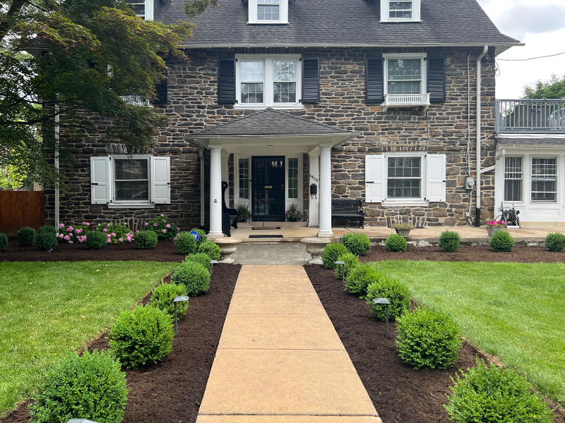 Boxwood-lined front walkway with structured planting beds and hardscape detailing in Overbrook Farms.