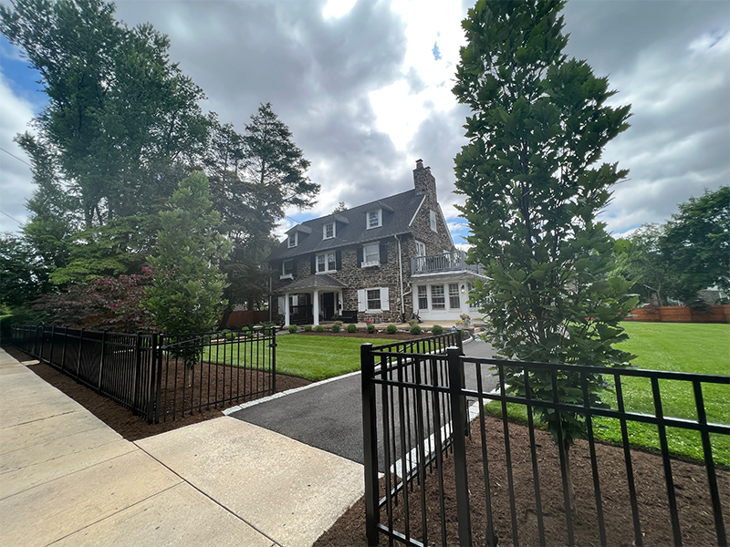 Alternative view of Kindred Spirit oak trees (Quercus x ‘Kindred Spirit’) framing the driveway entrance, with structured front yard plantings and integrated hardscape at Overbrook Farms.