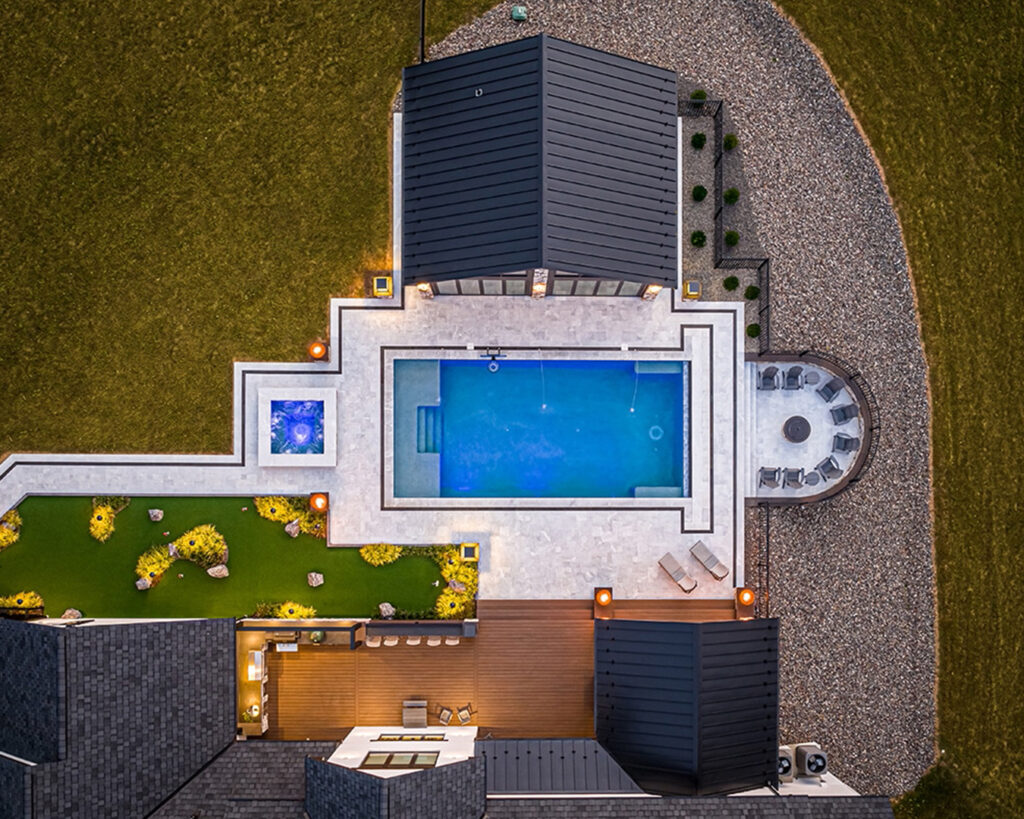 Aerial view of modern farmhouse landscape in Christiana, Pennsylvania, showing putting green, surrounding perennial plantings, pool, deck, fire pit, hardscaping, and detached gym