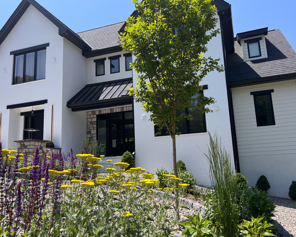 Perspective view of perennial plantings in bloom along the front entrance of a modern farmhouse landscape in Christiana, Pennsylvania
