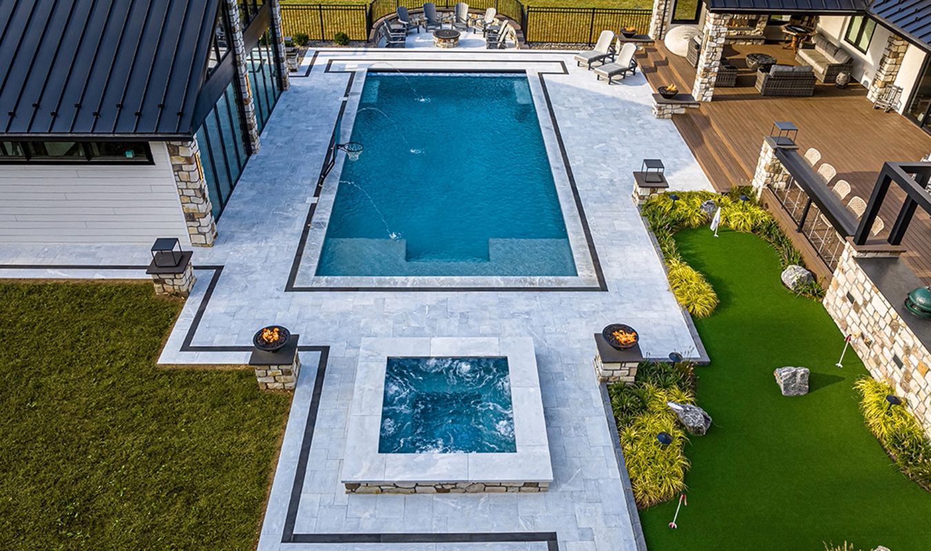 Aerial view of modern farmhouse landscape in Christiana, Pennsylvania, showing putting green, surrounding perennial plantings, pool, deck, fire pit, and detached gym